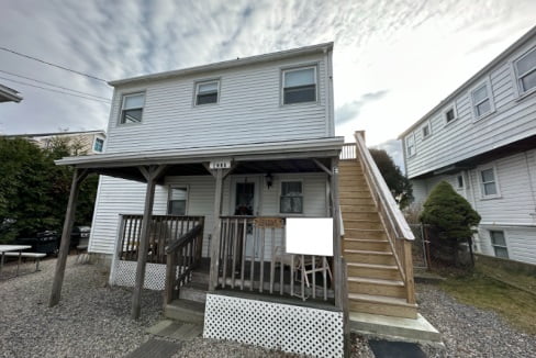 a two story house with a porch and stairs.
