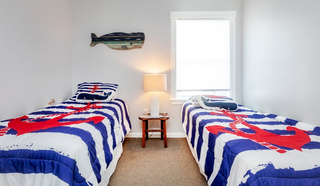 Two beds in a room with a nautical theme.
