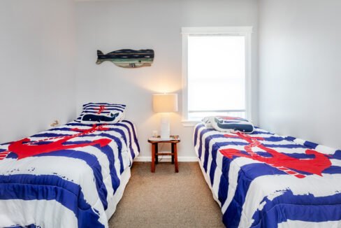 Two beds in a room with a nautical theme.