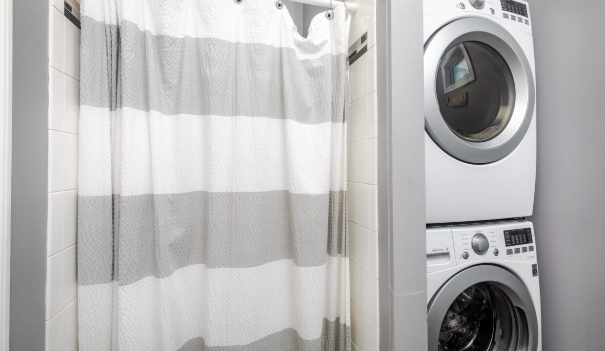 A laundry room with a washing machine and a shower curtain.