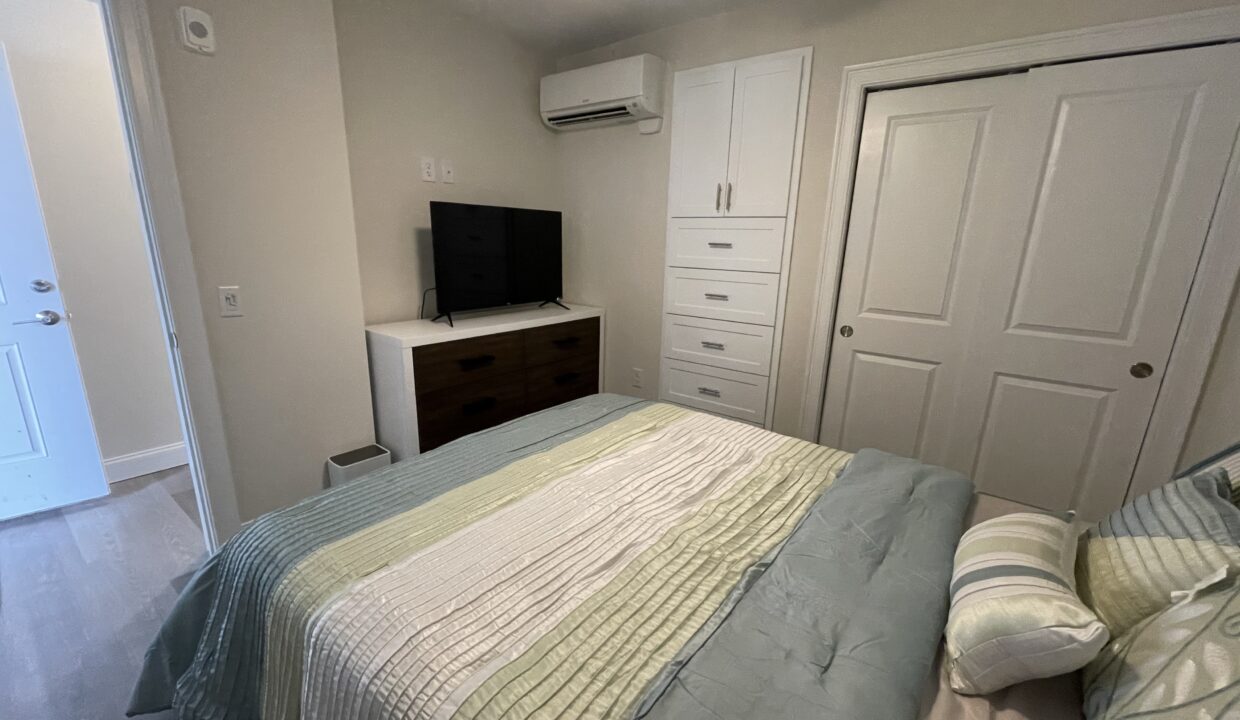 a bed room with a neatly made bed and a flat screen tv.