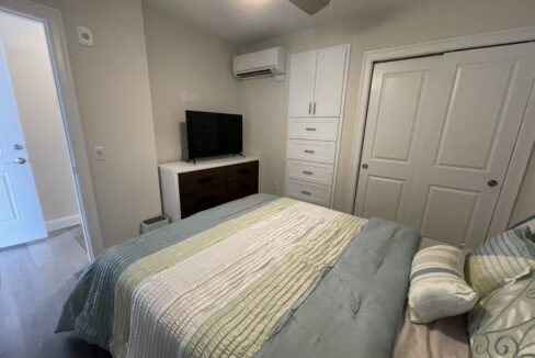 a bed room with a neatly made bed and a flat screen tv.