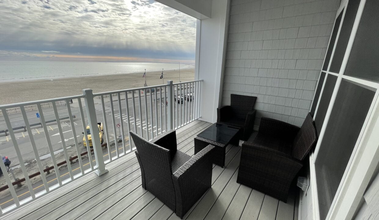 a balcony with wicker furniture and a view of the beach.