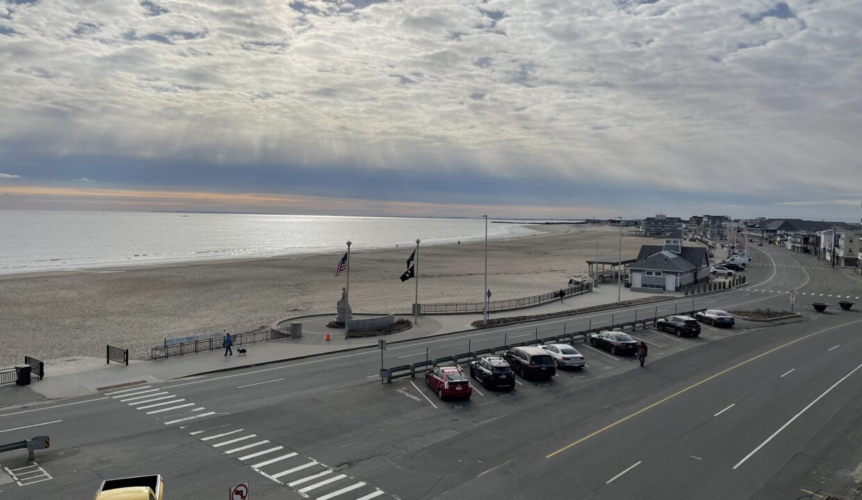 a parking lot next to a beach with cars parked on it.