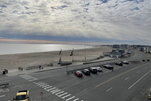 a parking lot next to a beach with cars parked on it.