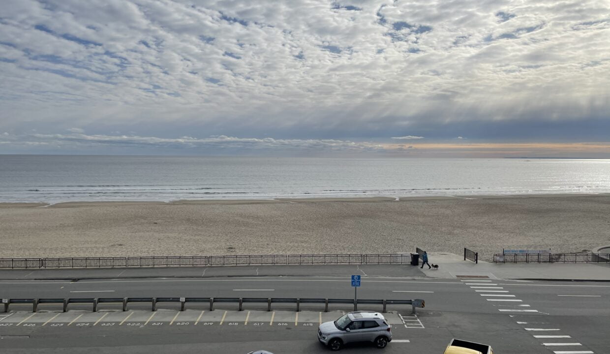 a parking lot next to a beach with cars parked in it.