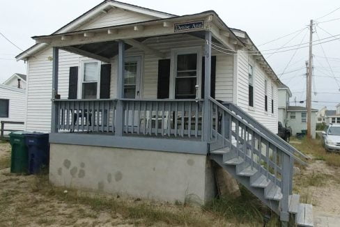 a small white house with a porch and stairs.