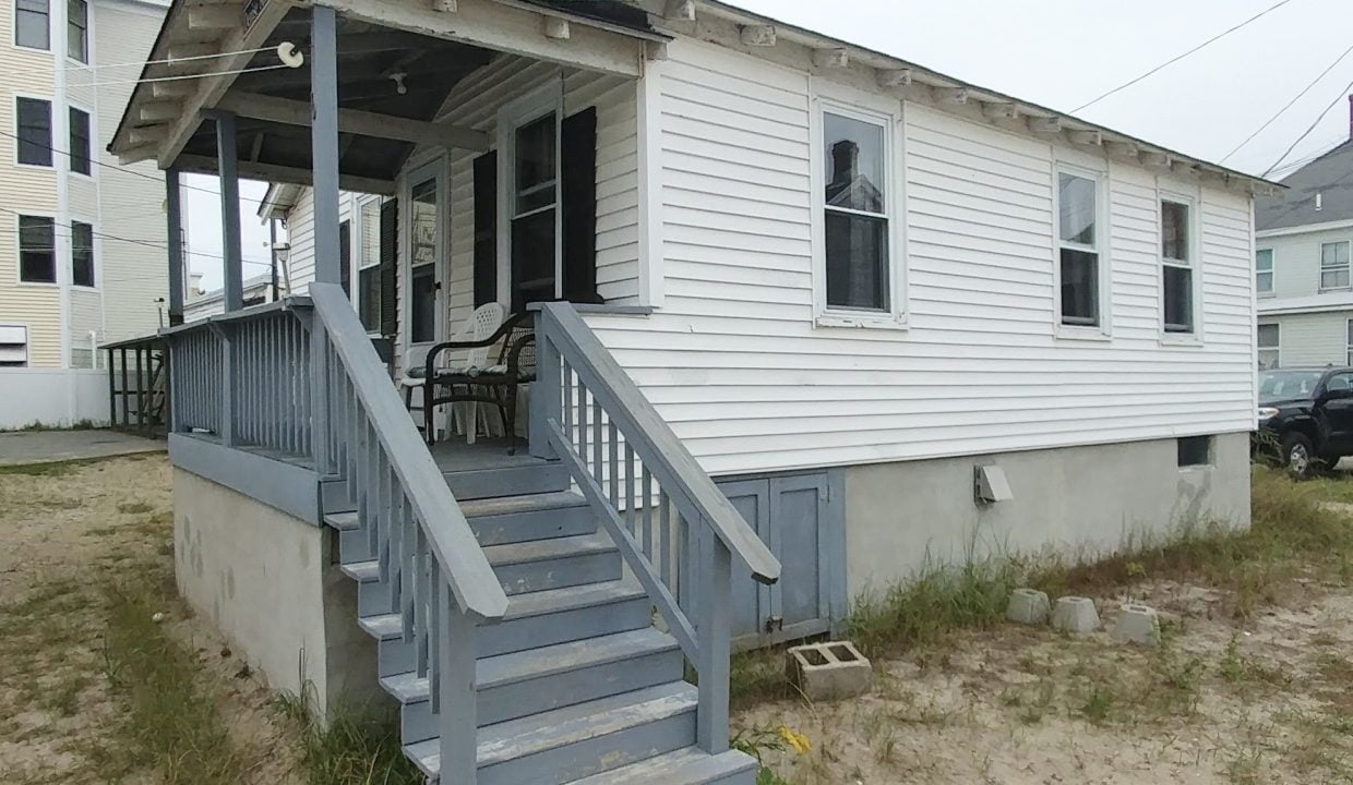 a small white house with a porch and stairs.