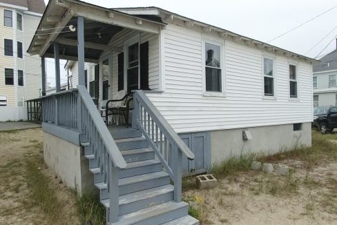 a small white house with a porch and stairs.