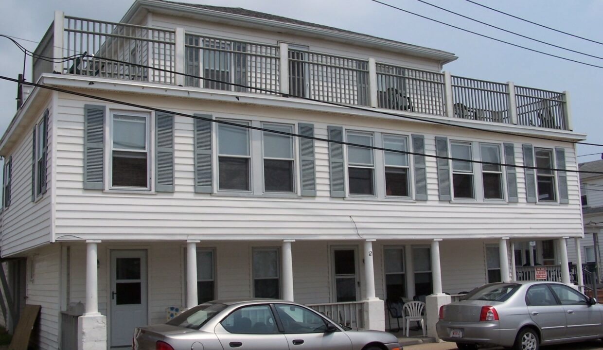 two cars parked in front of a two story house.