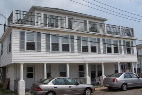 two cars parked in front of a two story house.