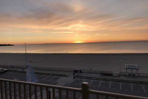 a view of a beach from a balcony at sunset.