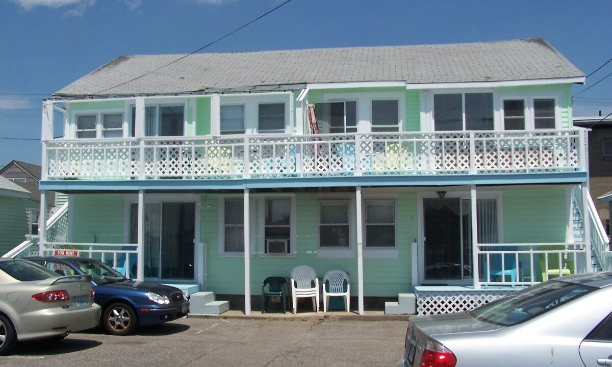 two cars parked in front of a two story house.