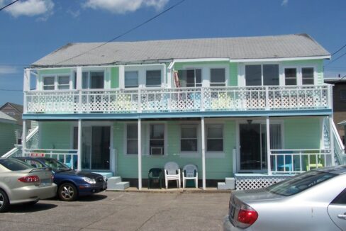 two cars parked in front of a two story house.