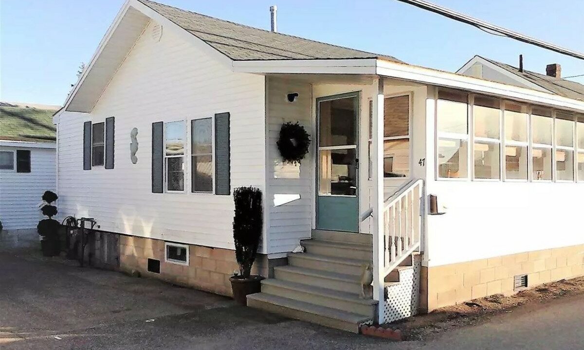 a small white house with a porch and stairs.