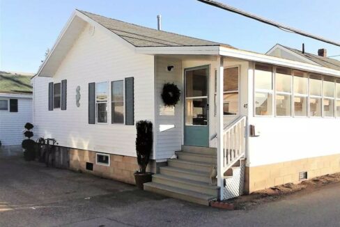 a small white house with a porch and stairs.