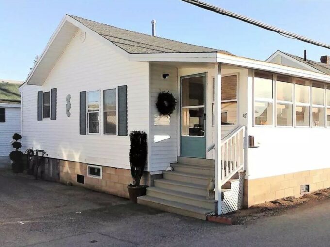 a small white house with a porch and stairs.