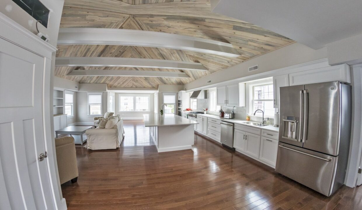 a large kitchen with a wooden ceiling and white cabinets.