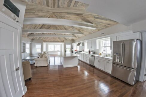 a large kitchen with a wooden ceiling and white cabinets.