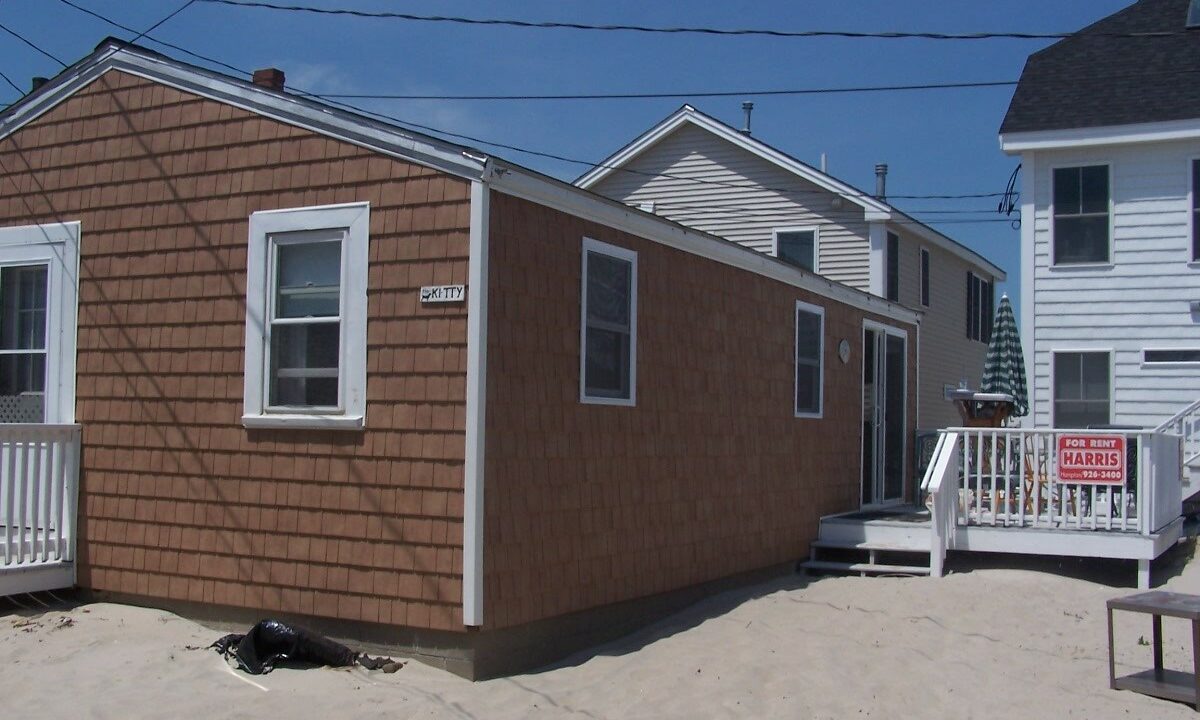 a small brown house with a white porch.