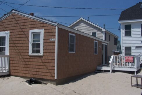 a small brown house with a white porch.