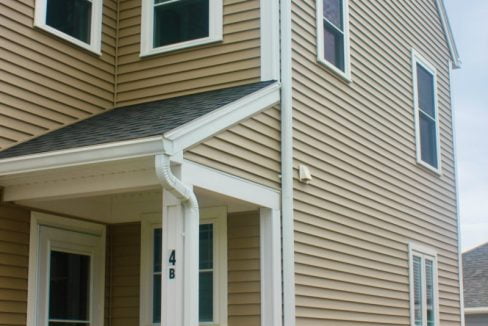 a brown house with white trim and a porch.