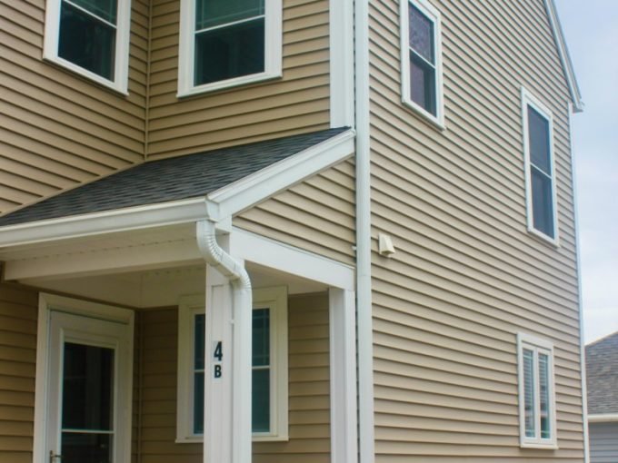 a brown house with white trim and a porch.