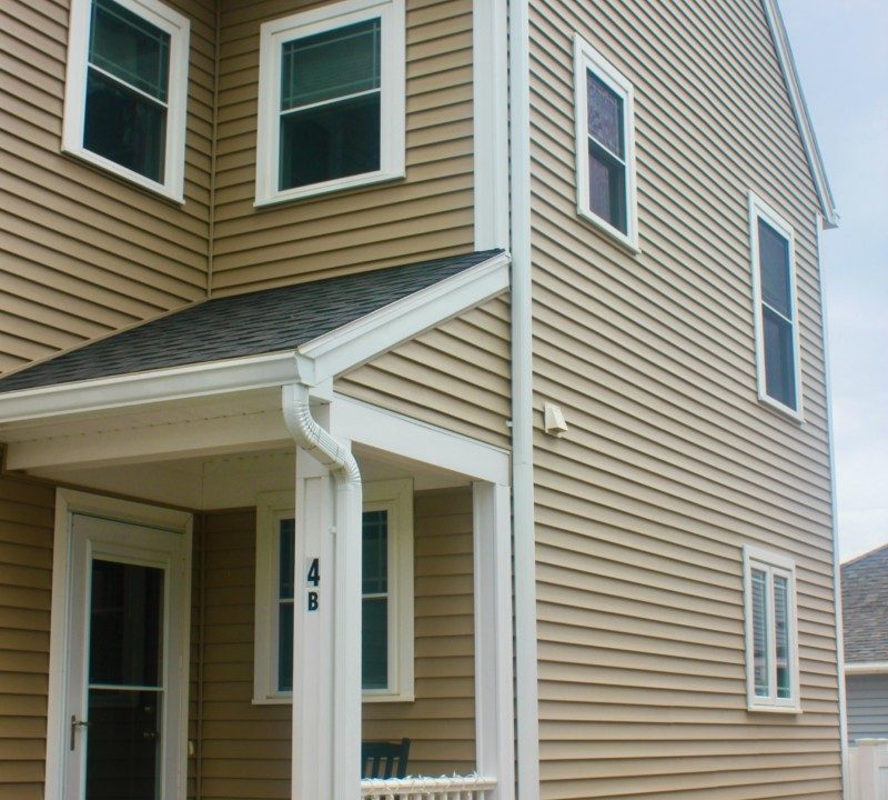 a brown house with white trim and a porch.