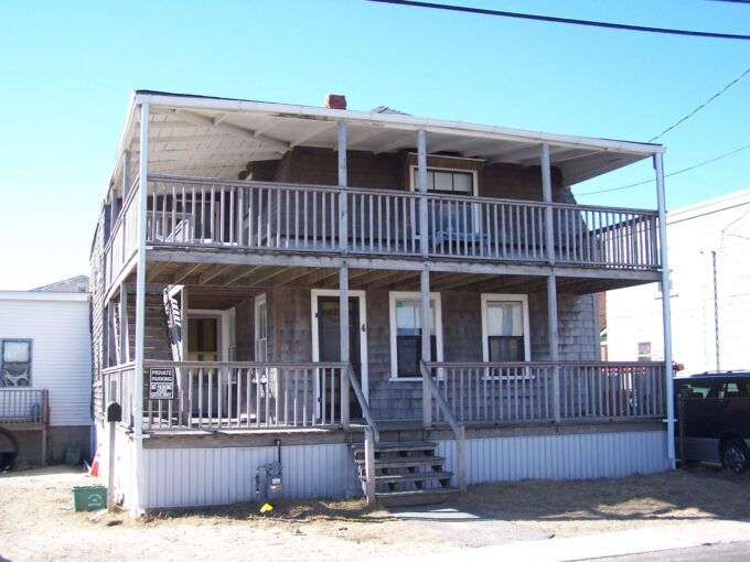 a two story house with a porch and stairs.