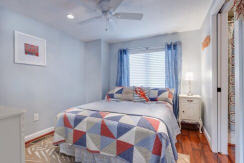 a bed room with a neatly made bed and a ceiling fan.