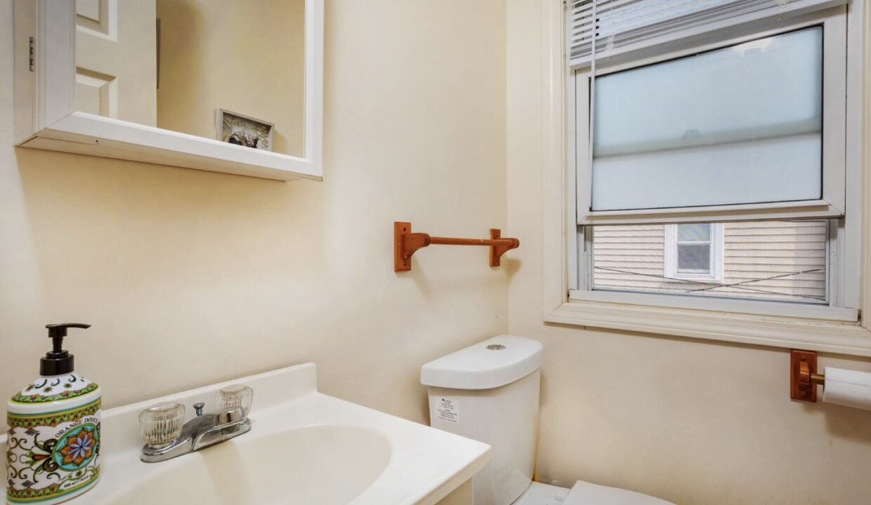 a bathroom with a toilet, sink, and window.