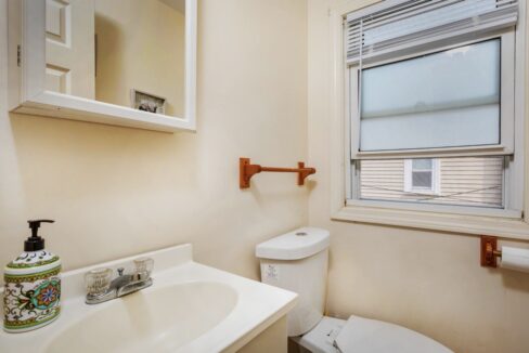 a bathroom with a toilet, sink, and window.