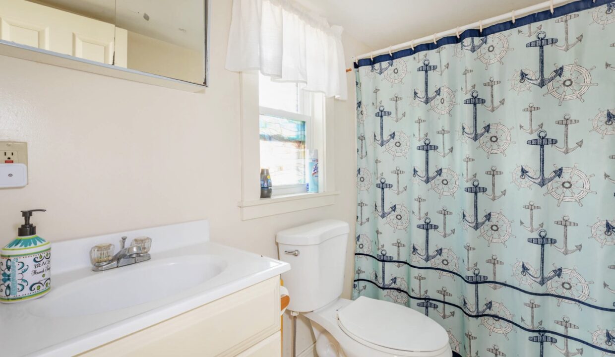 a bathroom with a toilet, sink, and shower curtain.