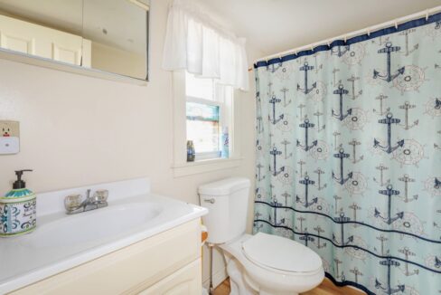 a bathroom with a toilet, sink, and shower curtain.