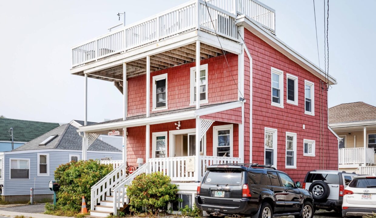 two cars parked in front of a red house.