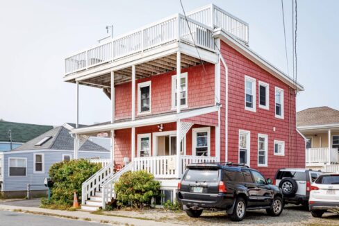 two cars parked in front of a red house.