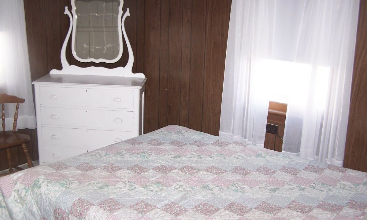 a bedroom with a bed, dresser and mirror.