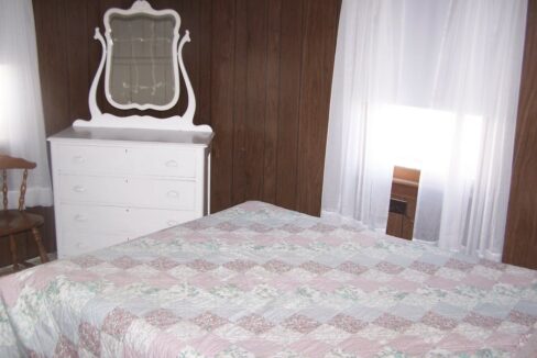 a bedroom with a bed, dresser and mirror.