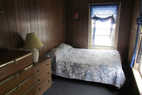 a bedroom with a bed, dresser and window.