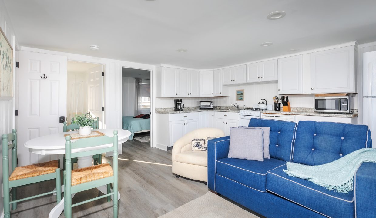 Bright modern living space with an open kitchen, a blue sofa, and a dining area.