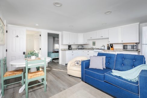 Bright modern living space with an open kitchen, a blue sofa, and a dining area.