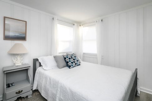 Bright and tidy bedroom with white linens and minimalist decor.