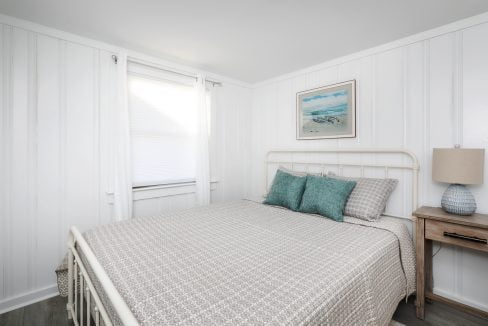 Bright, cozy bedroom with a white interior, double bed, and beach-themed decor.
