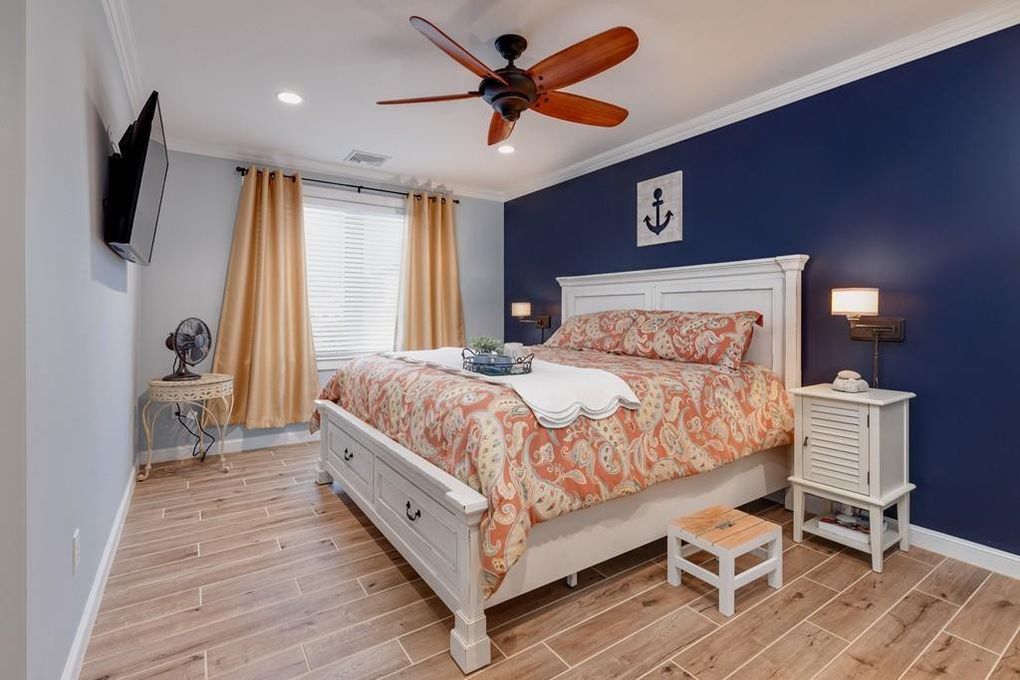a bed room with a neatly made bed and a ceiling fan.