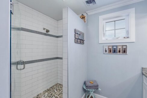 a bathroom with a walk in shower next to a sink.