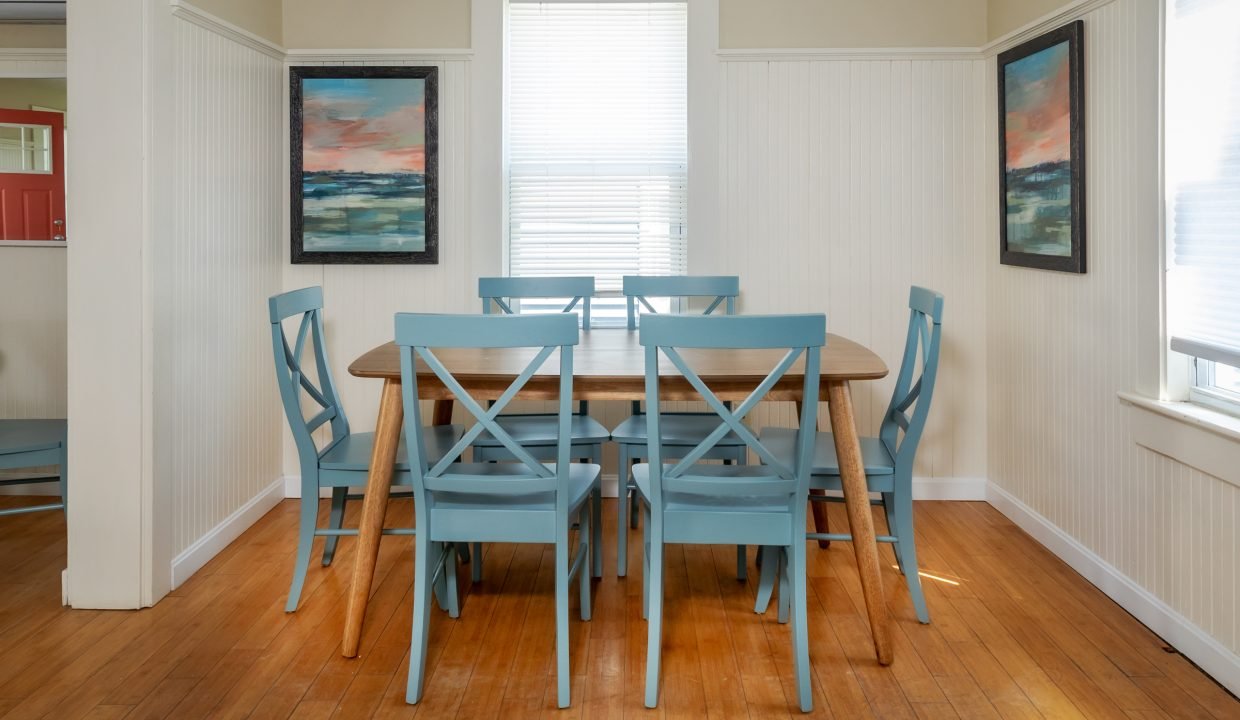 a dining room table with blue chairs and a picture on the wall.