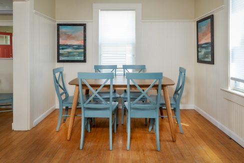 a dining room table with blue chairs and a picture on the wall.