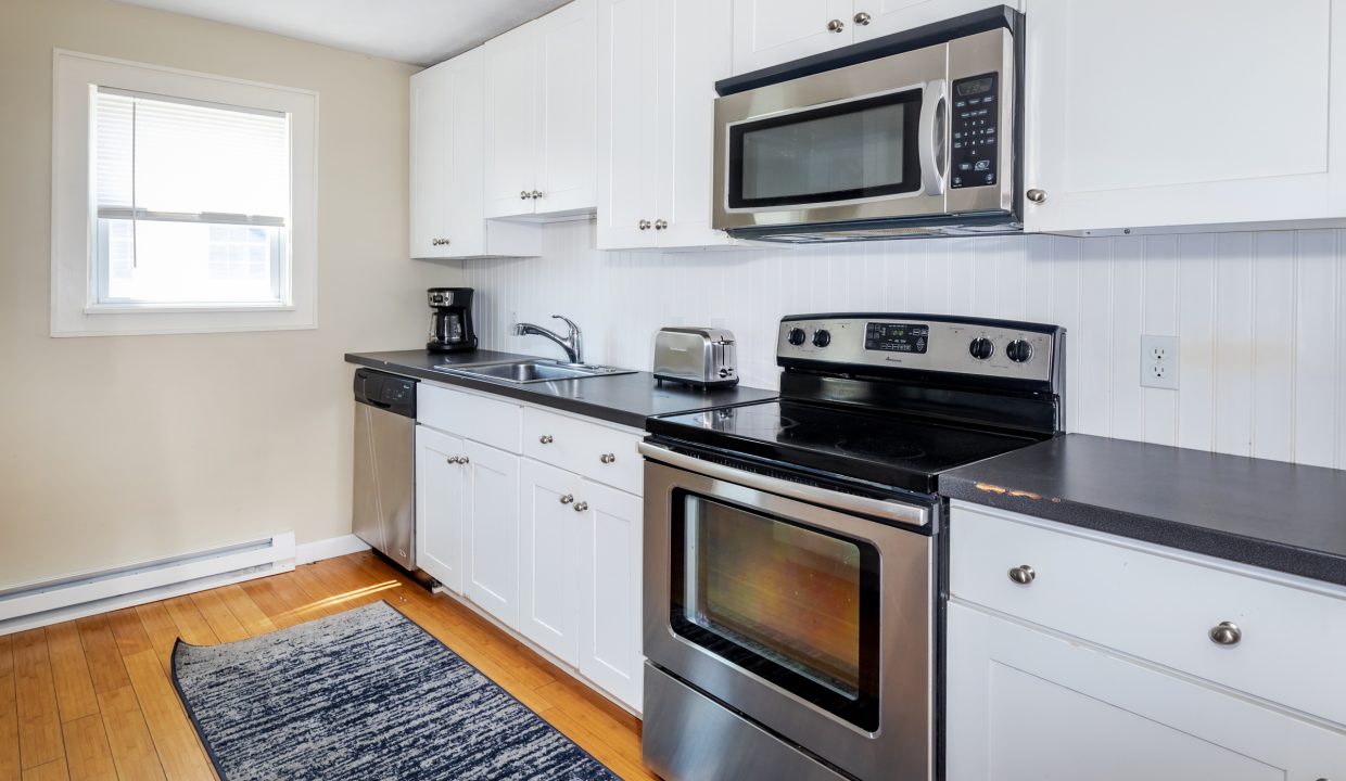 a kitchen with white cabinets and black counter tops.