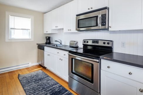 a kitchen with white cabinets and black counter tops.