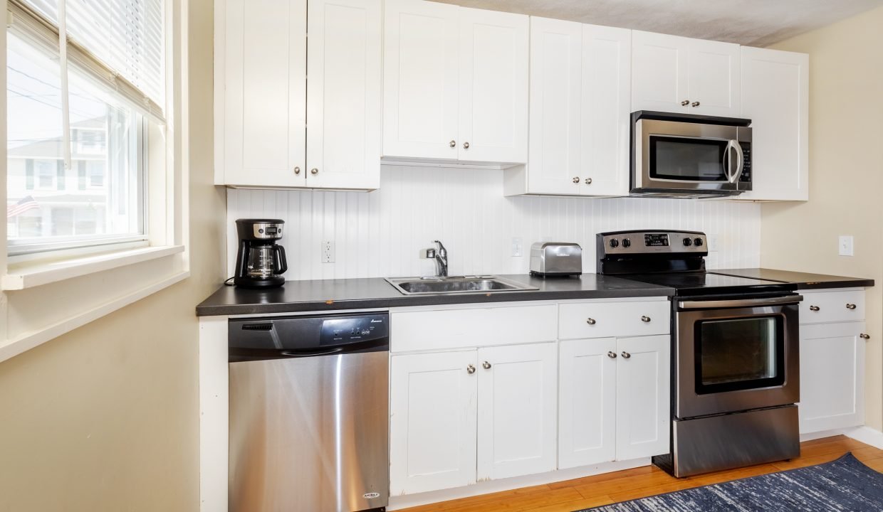 a kitchen with white cabinets and black counter tops.